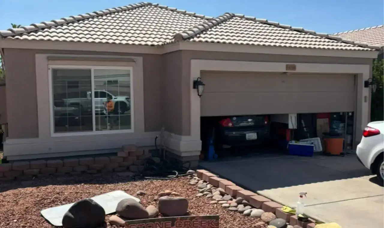 After: the same home repainted in a warm grey, with its tile roof above