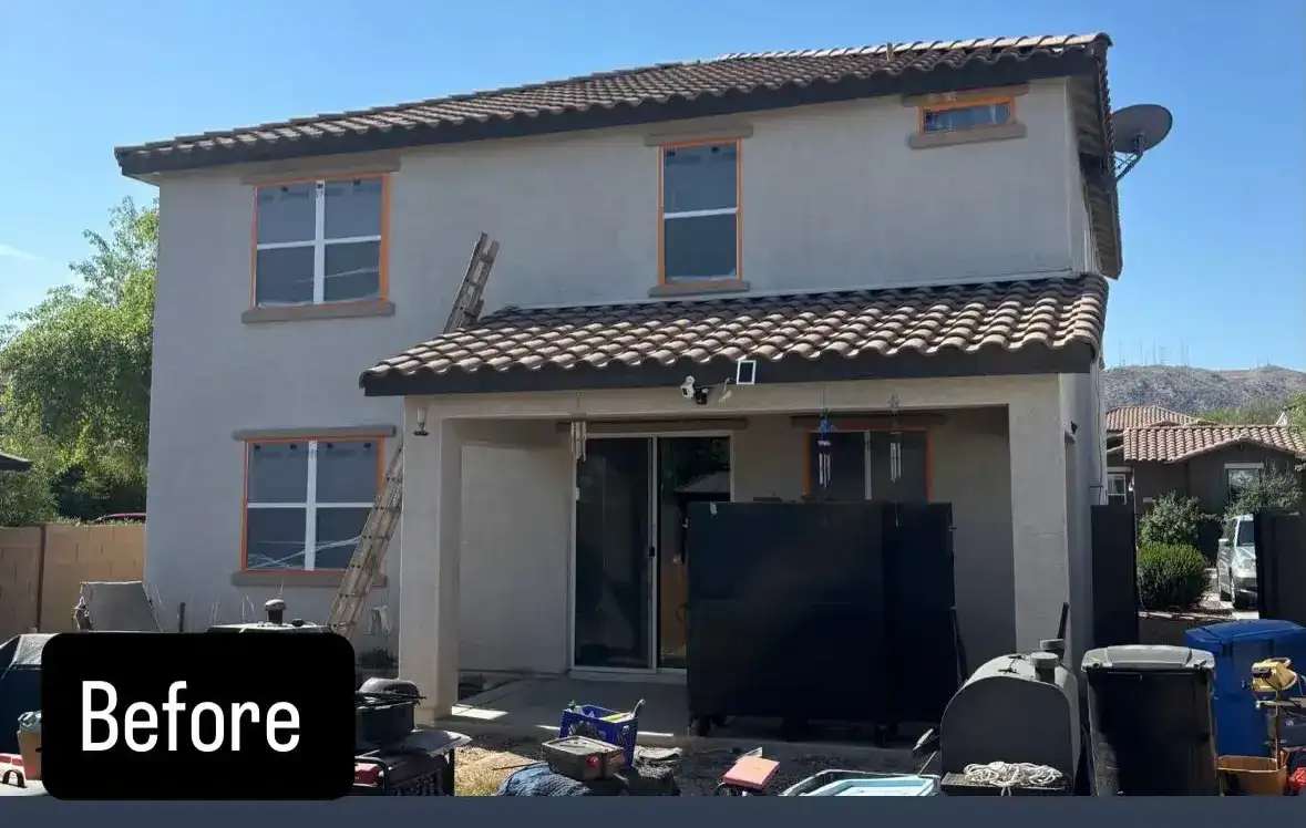 Before: back of a two-story stucco home with faded paint and windows taped for prep