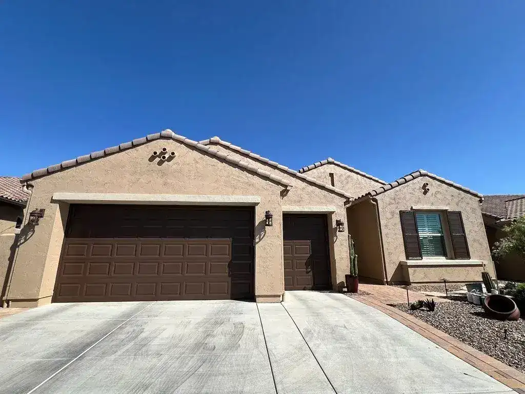 Front of a single-story stucco home with two brown garage doors after a fresh exterior repaint